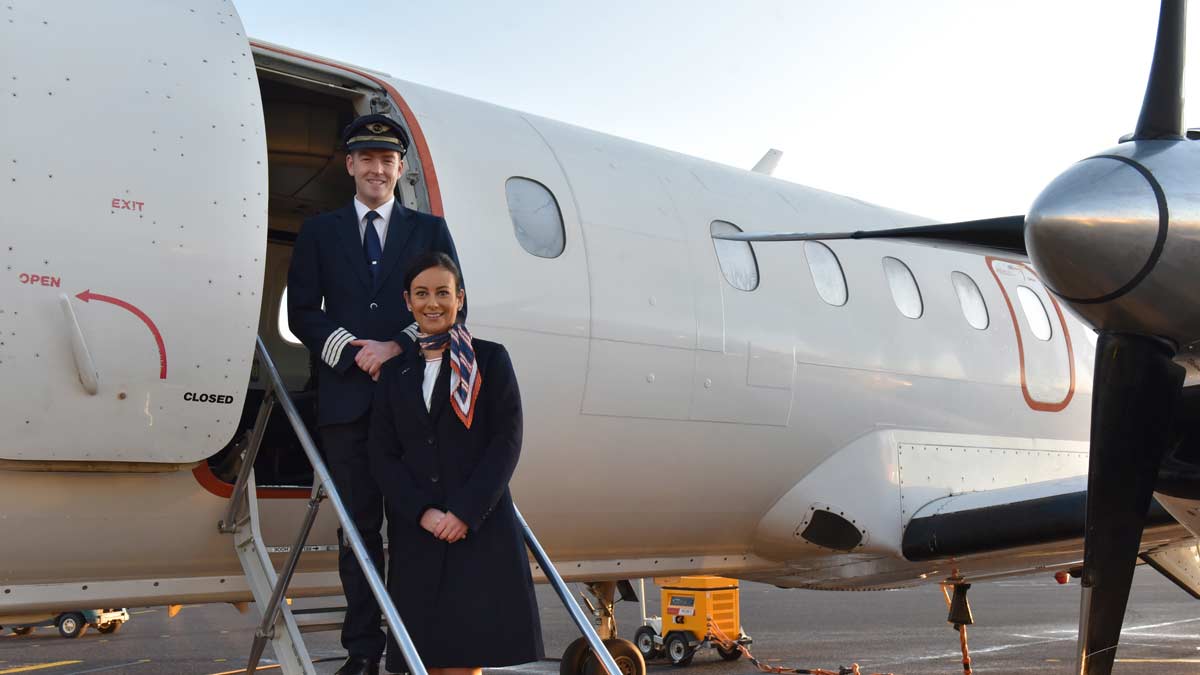 a man and woman standing in front of an airplane