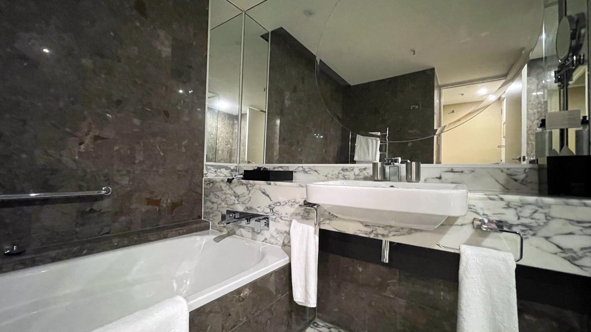 a bathroom with marble walls and a sink and tub