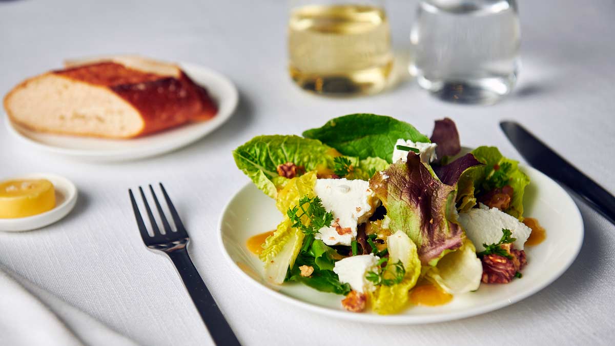 a plate of salad with fork and knife