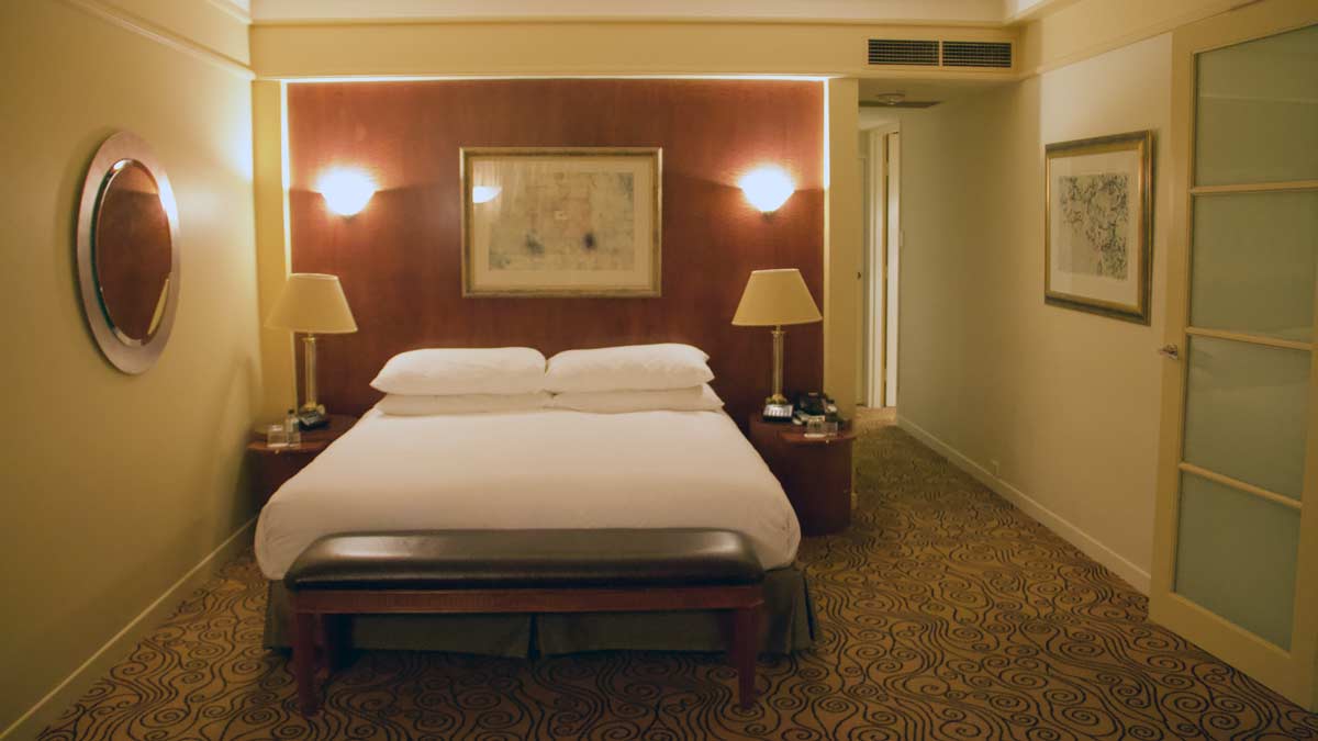 a bed with white sheets and lamps