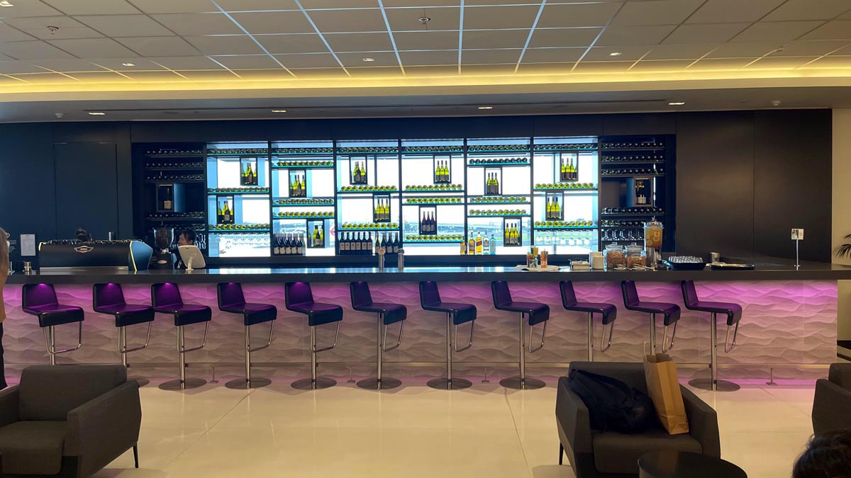 a bar with purple chairs and bottles