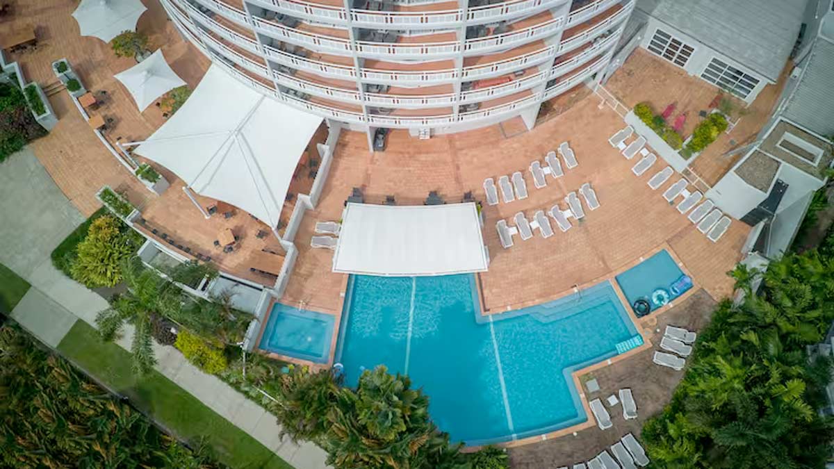 a pool and a building with trees and grass