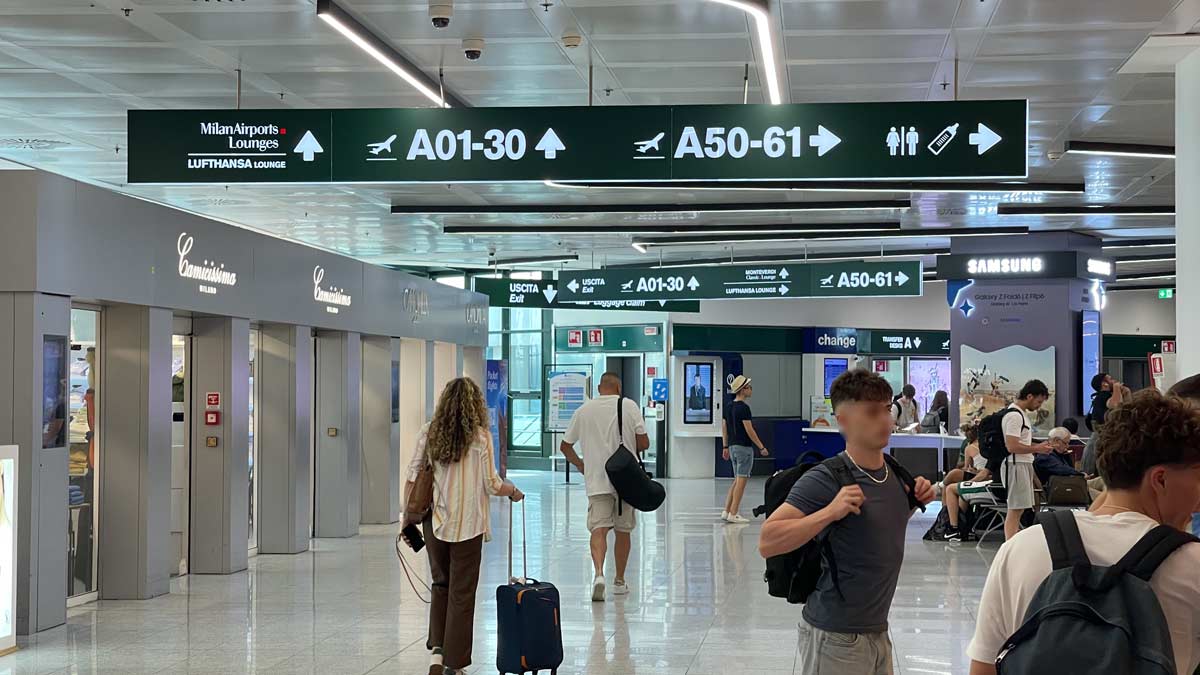 people in an airport with signs and people walking