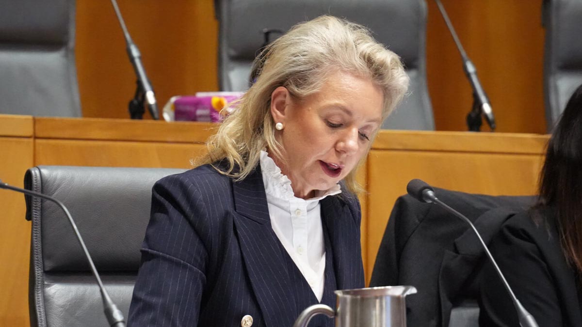 a woman in a suit sitting at a microphone