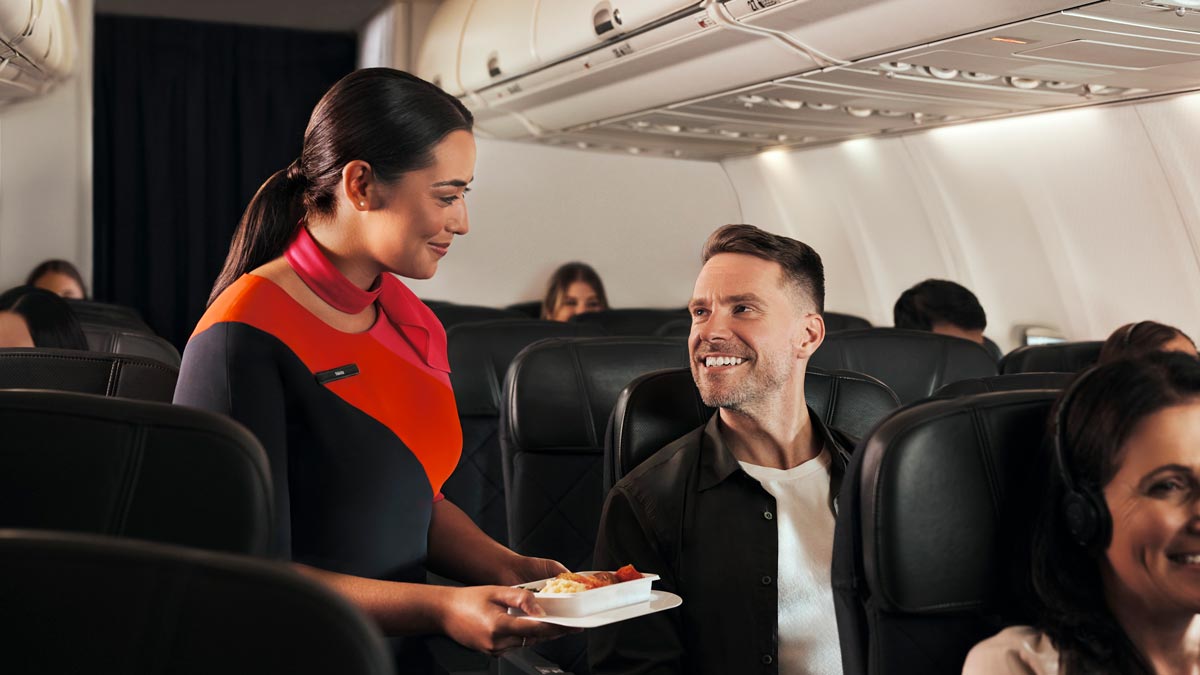 a woman serving food to a man on an airplane