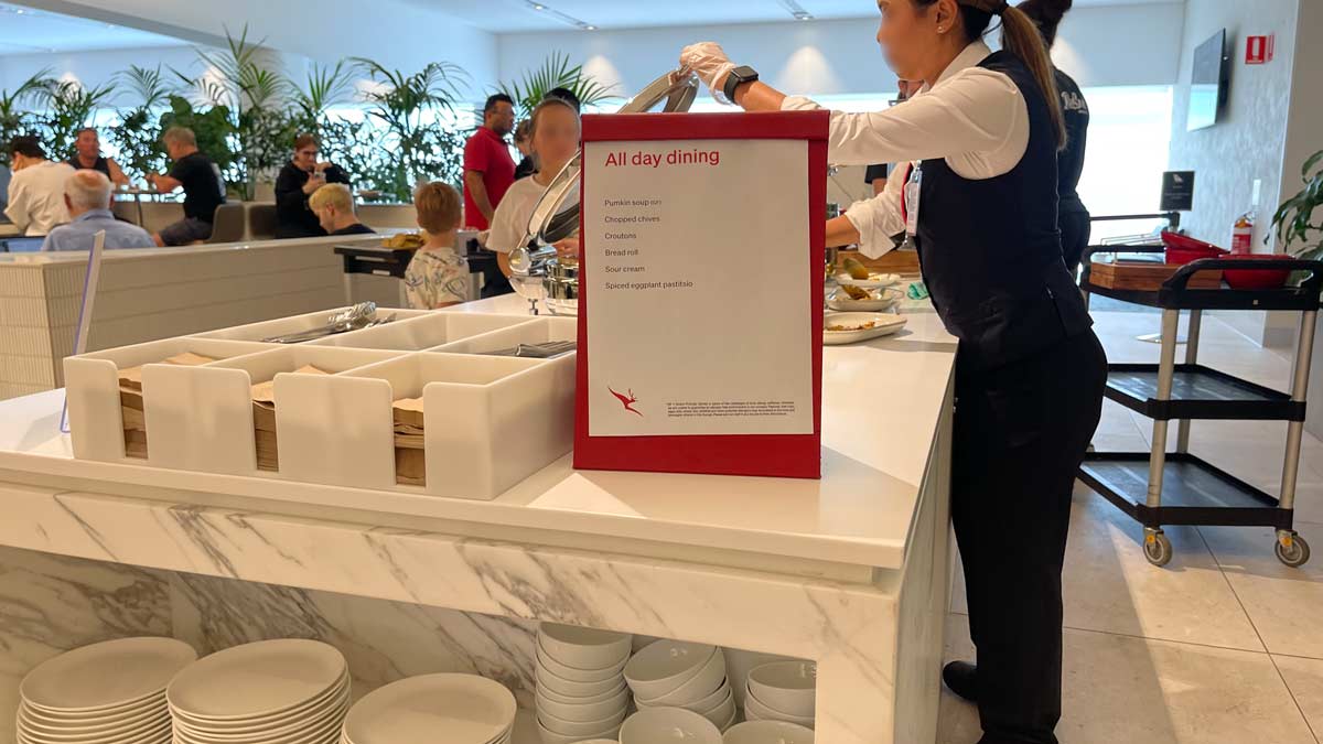 a woman holding a sign with a menu in the background