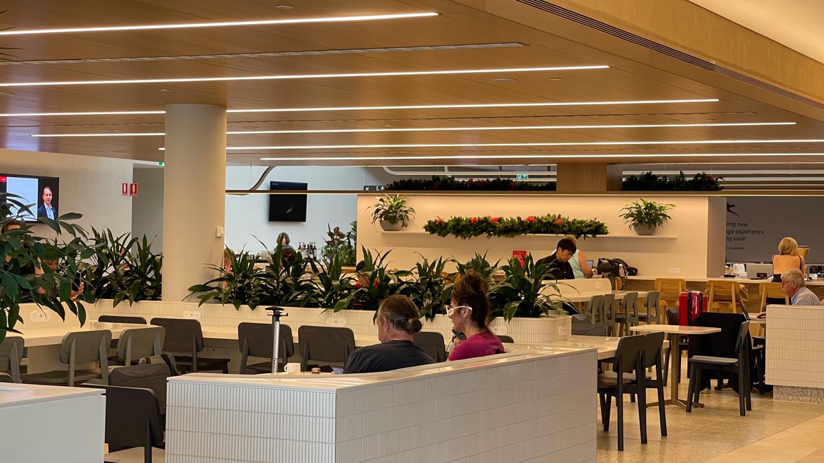 people sitting at tables in a room with plants