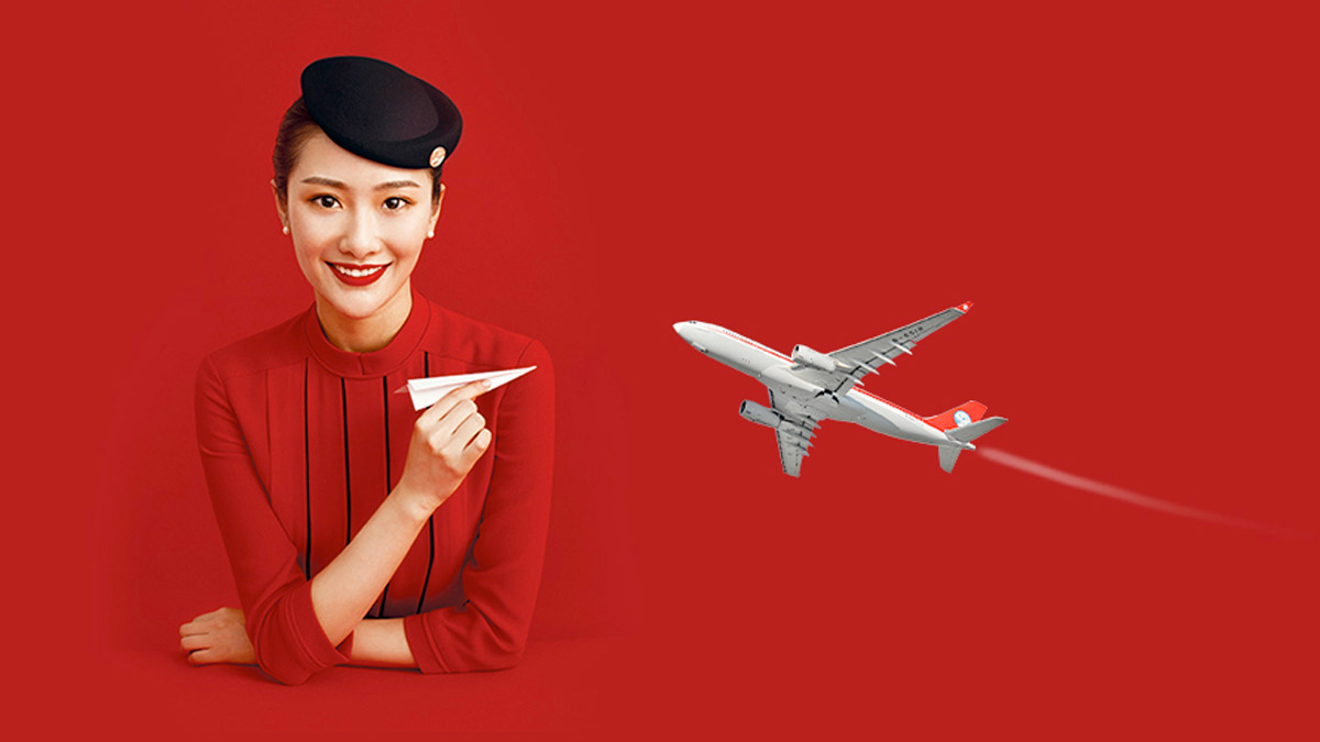 a woman in a red dress and a black hat holding a paper plane